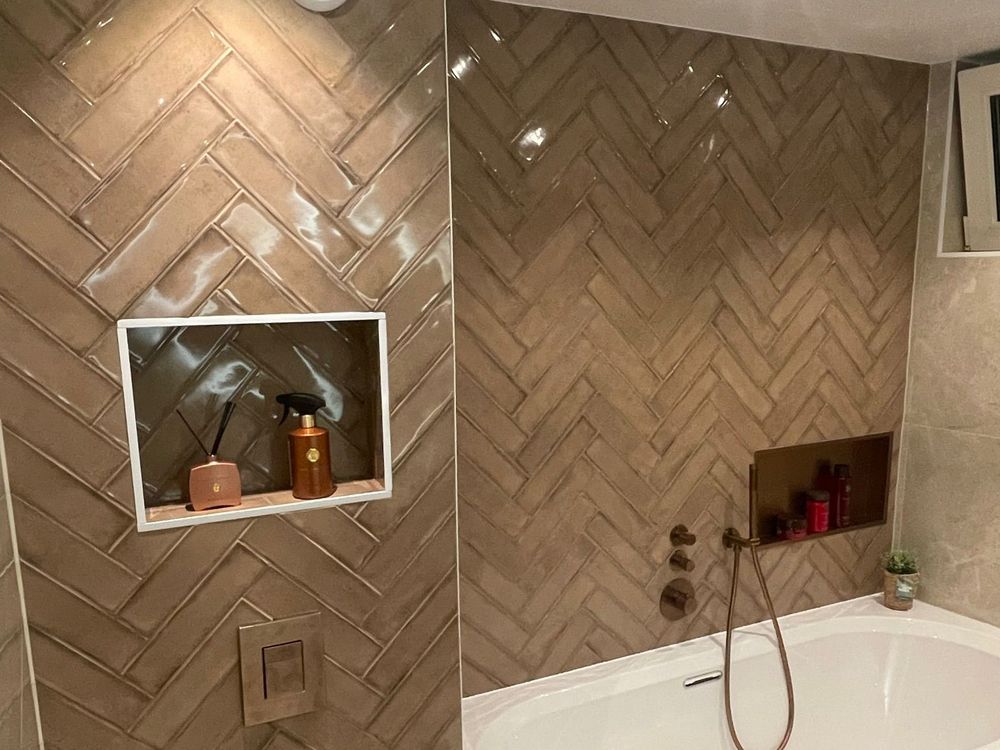 Badkamer met visgraat wandtegels, ligbad en zwevend toilet, gerenoveerd door Klusbedrijf H&H