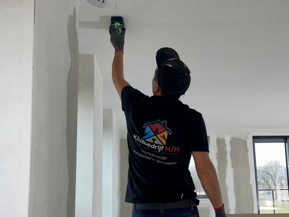 Medewerker van Klusbedrijf H&H werkt een wand af in een woning in aanbouw